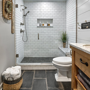 Foto di una stanza da bagno padronale country di medie dimensioni con consolle stile comò, ante con finitura invecchiata, piastrelle bianche, top in marmo, top bianco, un lavabo, mobile bagno freestanding, doccia alcova, WC a due pezzi, piastrelle in ceramica, pareti grigie, pavimento in gres porcellanato, pavimento nero, porta doccia a battente, panca da doccia, pareti in perlinato e lavabo sottopiano