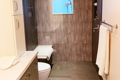 Example of a small trendy 3/4 multicolored tile and porcelain tile porcelain tile and gray floor bathroom design in Seattle with flat-panel cabinets, brown cabinets, a wall-mount toilet, pink walls, an undermount sink, quartz countertops and white countertops