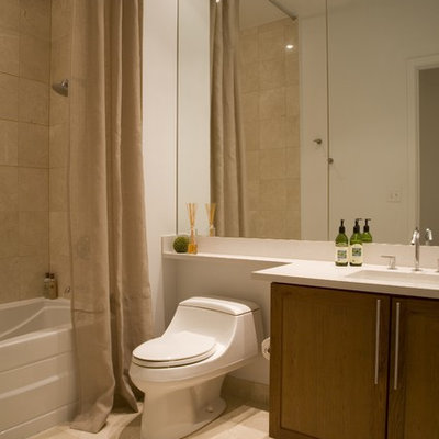 Example of a trendy beige tile tub/shower combo design in DC Metro with an integrated sink, shaker cabinets, medium tone wood cabinets, a one-piece toilet and white countertops