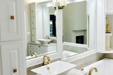 This is an example of a large classic ensuite bathroom in Dallas with recessed-panel cabinets, white cabinets, a corner bath, a walk-in shower, a one-piece toilet, white tiles, porcelain tiles, beige walls, porcelain flooring, a vessel sink and solid surface worktops.