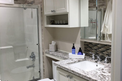 Bathroom - mid-sized traditional beige tile and stone tile linoleum floor, gray floor and single-sink bathroom idea in Portland with raised-panel cabinets, white cabinets, a two-piece toilet, beige walls, an undermount sink, granite countertops, gray countertops, a niche and a built-in vanity
