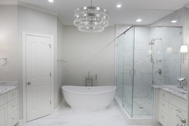 Example of a large transitional master white tile and porcelain tile porcelain tile and white floor bathroom design in Other with shaker cabinets, white cabinets, a two-piece toilet, beige walls, an undermount sink, marble countertops, a hinged shower door and white countertops