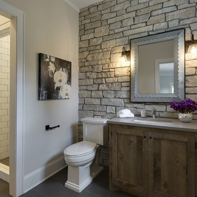 Example of a mid-sized farmhouse 3/4 white tile and ceramic tile porcelain tile and gray floor corner shower design in Minneapolis with medium tone wood cabinets, a two-piece toilet, gray walls, shaker cabinets, an undermount sink, quartz countertops, a hinged shower door and gray countertops