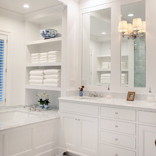 Diseño de cuarto de baño principal, tradicional, de tamaño medio, con armarios con paneles empotrados, puertas de armario blancas, bañera encastrada sin remate, paredes blancas, lavabo bajoencimera, suelo blanco, encimeras blancas, ducha empotrada, baldosas y/o azulejos de mármol, suelo de mármol, encimera de mármol y ducha con puerta con bisagras