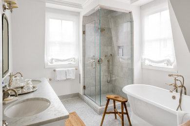 ニューヨークにあるトランジショナルスタイルのおしゃれなマスターバスルーム (シェーカースタイル扉のキャビネット、白いキャビネット、置き型浴槽、コーナー設置型シャワー、グレーのタイル、白い壁、アンダーカウンター洗面器、グレーの床、開き戸のシャワー) の写真