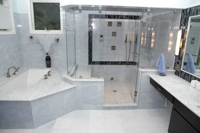Cette image montre une grande salle de bain principale design avec un lavabo encastré, une baignoire encastrée et un mur bleu.