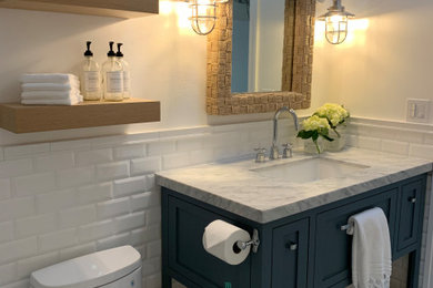 Inspiration for a small coastal 3/4 white tile and subway tile porcelain tile, gray floor and single-sink shower bench remodel in San Diego with shaker cabinets, blue cabinets, a one-piece toilet, white walls, an undermount sink, marble countertops, a hinged shower door, gray countertops and a freestanding vanity