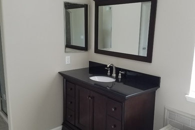 Bathroom - mid-sized contemporary master porcelain tile and beige floor bathroom idea in Los Angeles with furniture-like cabinets, brown cabinets, a two-piece toilet, beige walls, an undermount sink, quartz countertops, a hinged shower door and black countertops