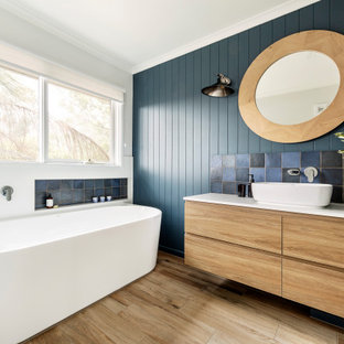 Design ideas for a contemporary master bathroom in Melbourne with flat-panel cabinets, light wood cabinets, a freestanding tub, multi-coloured tile, green walls, a vessel sink, beige floor and white benchtops.