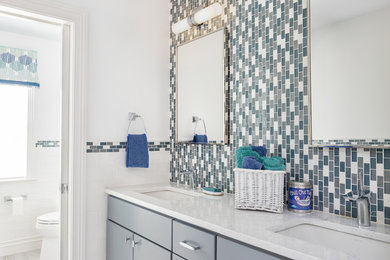 Bathroom - mid-sized contemporary kids' blue tile and subway tile ceramic tile and gray floor bathroom idea in New York with flat-panel cabinets, blue cabinets, a one-piece toilet, white walls, an undermount sink, quartz countertops, a hinged shower door and white countertops