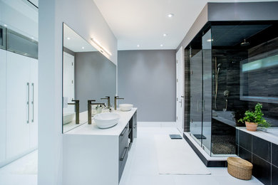 Cette photo montre une grande salle de bain principale moderne avec un placard à porte plane, des portes de placard blanches, un carrelage noir, des carreaux de céramique, un mur gris, une vasque, un plan de toilette en quartz modifié, un sol blanc et un plan de toilette blanc.