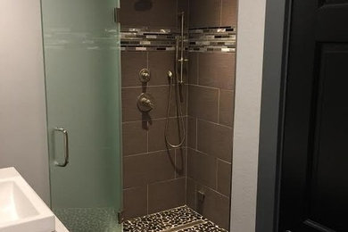 Example of a mid-sized trendy 3/4 ceramic tile and multicolored tile ceramic tile corner shower design in Other with black cabinets, gray walls, a vessel sink, solid surface countertops and a hinged shower door
