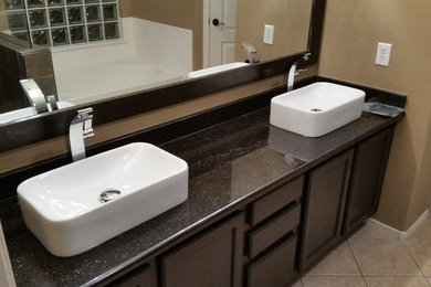 Example of a mid-sized transitional master ceramic tile alcove bathtub design in Phoenix with brown walls, a vessel sink, recessed-panel cabinets, dark wood cabinets and granite countertops