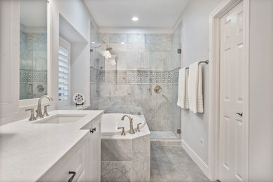 Example of a transitional master black and white tile and marble tile porcelain tile, gray floor and double-sink drop-in bathtub design in Houston with recessed-panel cabinets, white cabinets, blue walls, an undermount sink, quartz countertops, a hinged shower door and white countertops