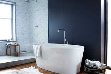 Idee per una stanza da bagno minimal con vasca freestanding, doccia aperta, piastrelle bianche, pareti nere, pavimento in legno massello medio e doccia aperta
