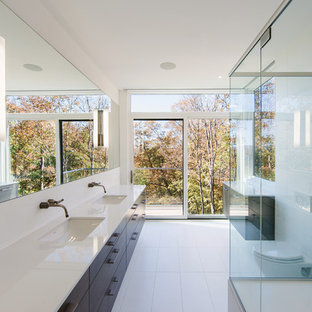 Foto de cuarto de baño minimalista, grande, con armarios con paneles lisos, puertas de armario de madera en tonos medios, ducha esquinera, sanitario de pared, baldosas y/o azulejos blancos, paredes blancas, lavabo bajoencimera y suelo de baldosas de cerámica
