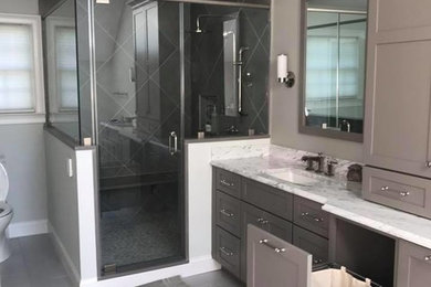 Mid-sized trendy master gray tile and ceramic tile porcelain tile and gray floor corner shower photo in Philadelphia with brown cabinets, a one-piece toilet, gray walls, an undermount sink, quartzite countertops and a hinged shower door