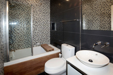 ワシントンD.C.にある高級な小さなコンテンポラリースタイルのおしゃれなバスルーム (浴槽なし) (フラットパネル扉のキャビネット、白いキャビネット、ドロップイン型浴槽、シャワー付き浴槽	、分離型トイレ、ベッセル式洗面器、人工大理石カウンター、グレーの壁) の写真