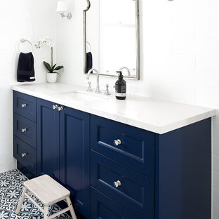 Transitional bathroom in Brisbane with recessed-panel cabinets, blue cabinets, white tile, white walls, an undermount sink, multi-coloured floor and white benchtops.