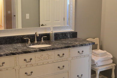 Inspiration for a mid-sized transitional 3/4 ceramic tile and gray floor bathroom remodel in Other with gray walls, an undermount sink, flat-panel cabinets, distressed cabinets, soapstone countertops, black countertops and a two-piece toilet