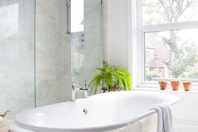 Photo of a large contemporary family bathroom in Cheshire with a freestanding bath, a walk-in shower, a two-piece toilet, marble tiles, blue walls, painted wood flooring, a wall-mounted sink, white floors and an open shower.
