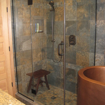 Glass enclosed shower with manufactured slate tile.