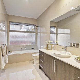 This is an example of a mid-sized contemporary bathroom in Melbourne with a drop-in tub, beige tile, a vessel sink, beige floor, flat-panel cabinets, engineered quartz benchtops, dark wood cabinets, a shower/bathtub combo and white benchtops.