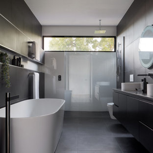 Design ideas for a contemporary master bathroom in Melbourne with flat-panel cabinets, black cabinets, a freestanding tub, gray tile, a vessel sink, grey benchtops, a double vanity, a floating vanity, a niche, an alcove shower, a wall-mount toilet, porcelain tile, black walls, porcelain floors, engineered quartz benchtops, black floor and an open shower.