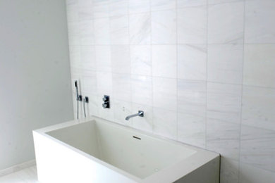 This is an example of a large modern ensuite bathroom in Chicago with a built-in sink, flat-panel cabinets, white cabinets, marble worktops, a freestanding bath, a corner shower, a one-piece toilet, white tiles, white walls and marble flooring.