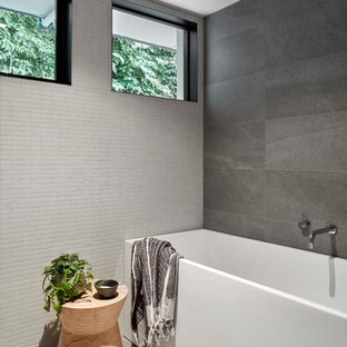 Photo of a small contemporary kids bathroom in Melbourne with a freestanding tub, gray tile, grey floor, furniture-like cabinets, black cabinets, a shower/bathtub combo, a wall-mount toilet, ceramic tile, grey walls, cement tiles, an integrated sink, solid surface benchtops, an open shower, white benchtops, a single vanity and a floating vanity.