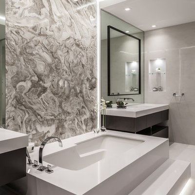 Example of a large trendy master beige tile and ceramic tile cement tile floor and beige floor wet room design in Miami with flat-panel cabinets, dark wood cabinets, an undermount tub, a one-piece toilet, beige walls, an integrated sink and white countertops