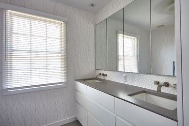 Bathroom photo in New York with flat-panel cabinets, white cabinets, quartz countertops and gray countertops