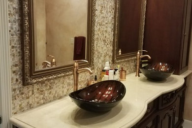 Example of a mid-sized mountain style master beige tile and mosaic tile ceramic tile and beige floor bathroom design in Houston with recessed-panel cabinets, dark wood cabinets, brown walls, a vessel sink and quartz countertops