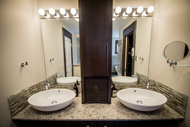 Modelo de cuarto de baño principal clásico de tamaño medio con lavabo sobreencimera, armarios con paneles lisos, puertas de armario de madera en tonos medios, encimera de cuarzo compacto, baldosas y/o azulejos marrones y paredes beige