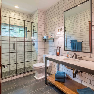 Mittelgroßes Industrial Duschbad mit verzierten Schränken, schwarzen Schränken, Duschnische, Wandtoilette mit Spülkasten, weißen Fliesen, Metrofliesen, weißer Wandfarbe, Porzellan-Bodenfliesen, Unterbauwaschbecken, Marmor-Waschbecken/Waschtisch, grauem Boden, Falttür-Duschabtrennung und weißer Waschtischplatte in Chicago
