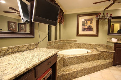 Inspiration for a large southwestern master stone slab cement tile floor and beige floor bathroom remodel in Dallas with recessed-panel cabinets, dark wood cabinets, an undermount tub, green walls, an undermount sink, granite countertops and beige countertops