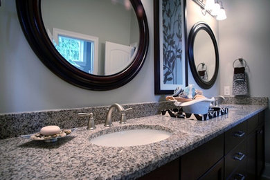 Ejemplo de cuarto de baño principal actual con armarios con paneles lisos, puertas de armario de madera en tonos medios, encimera de granito, paredes blancas y lavabo bajoencimera