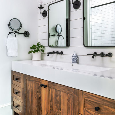 Example of a transitional master black floor, double-sink and shiplap wall bathroom design in Atlanta with shaker cabinets, medium tone wood cabinets, white walls, a trough sink, white countertops and a freestanding vanity