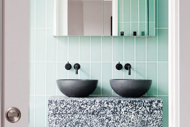Cette image montre une salle de bain design de taille moyenne avec une vasque, un carrelage vert, des carreaux de céramique, un mur vert et un sol multicolore.