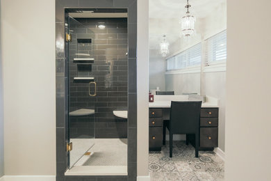 Example of a mid-sized transitional master ceramic tile cement tile floor and multicolored floor alcove shower design in Indianapolis with flat-panel cabinets, black cabinets, gray walls, solid surface countertops, an undermount sink and a hinged shower door