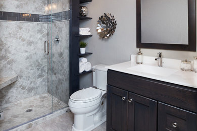 Idée de décoration pour une grande salle de bain tradition en bois foncé avec un placard à porte shaker, WC séparés, un carrelage gris, des dalles de pierre, un sol en carrelage de porcelaine, un lavabo intégré, un plan de toilette en quartz modifié, un sol beige, une cabine de douche à porte battante et un mur gris.