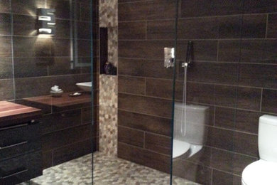 Large trendy brown tile and porcelain tile porcelain tile walk-in shower photo in DC Metro with flat-panel cabinets, gray cabinets, a two-piece toilet, gray walls, a vessel sink and wood countertops