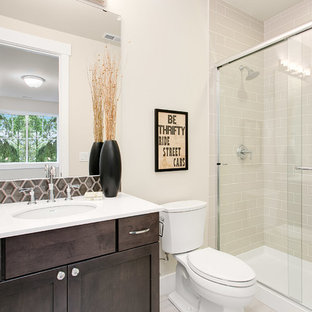 Ispirazione per una piccola stanza da bagno con doccia american style con ante in stile shaker, ante in legno bruno, doccia alcova, WC a due pezzi, piastrelle grigie, piastrelle in gres porcellanato, pareti beige, pavimento in gres porcellanato, lavabo sottopiano e top in superficie solida