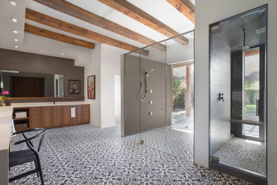 Inspiration for a large modern ensuite bathroom in Phoenix with flat-panel cabinets, medium wood cabinets, solid surface worktops, cement tiles, a built-in shower, white walls, cement flooring, a submerged sink, multi-coloured floors and a hinged door.