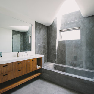 Tub/shower combo - modern concrete floor tub/shower combo idea in Los Angeles with flat-panel cabinets, medium tone wood cabinets and white countertops