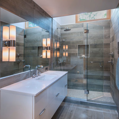 Large trendy 3/4 gray tile and ceramic tile ceramic tile alcove shower photo in Burlington with flat-panel cabinets, white cabinets, gray walls, solid surface countertops, a one-piece toilet and an undermount sink