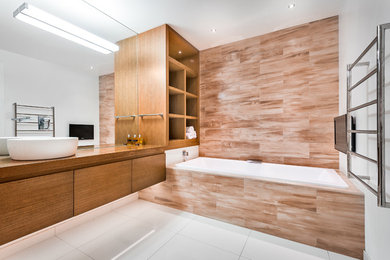 Contemporary bathroom in Auckland with a vessel sink, a built-in bath, flat-panel cabinets, medium wood cabinets, wooden worktops, multi-coloured tiles and porcelain tiles.