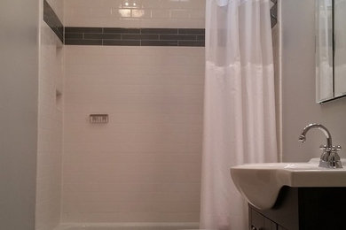 Cette photo montre une salle de bain chic en bois foncé de taille moyenne avec un placard avec porte à panneau encastré, un combiné douche/baignoire, un carrelage blanc, des carreaux de céramique, un sol en carrelage de porcelaine, un lavabo intégré, WC séparés et un mur gris.