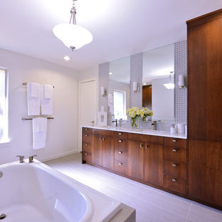 Foto di una grande stanza da bagno padronale design con lavabo sottopiano, ante lisce, ante in legno bruno, vasca da incasso, piastrelle grigie, piastrelle di vetro, pareti bianche e top in marmo
