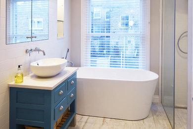 Small contemporary family bathroom in London with freestanding cabinets, blue cabinets, a freestanding bath, a built-in shower, white tiles, laminate floors, white floors and white worktops.